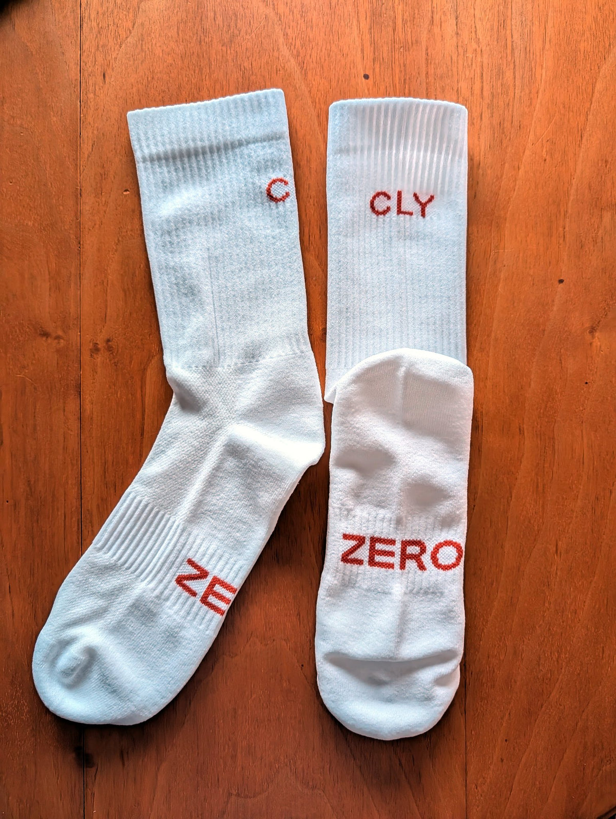 Par de calcetines CLY ZERO blancos estirados, con los logos CLY y ZERO